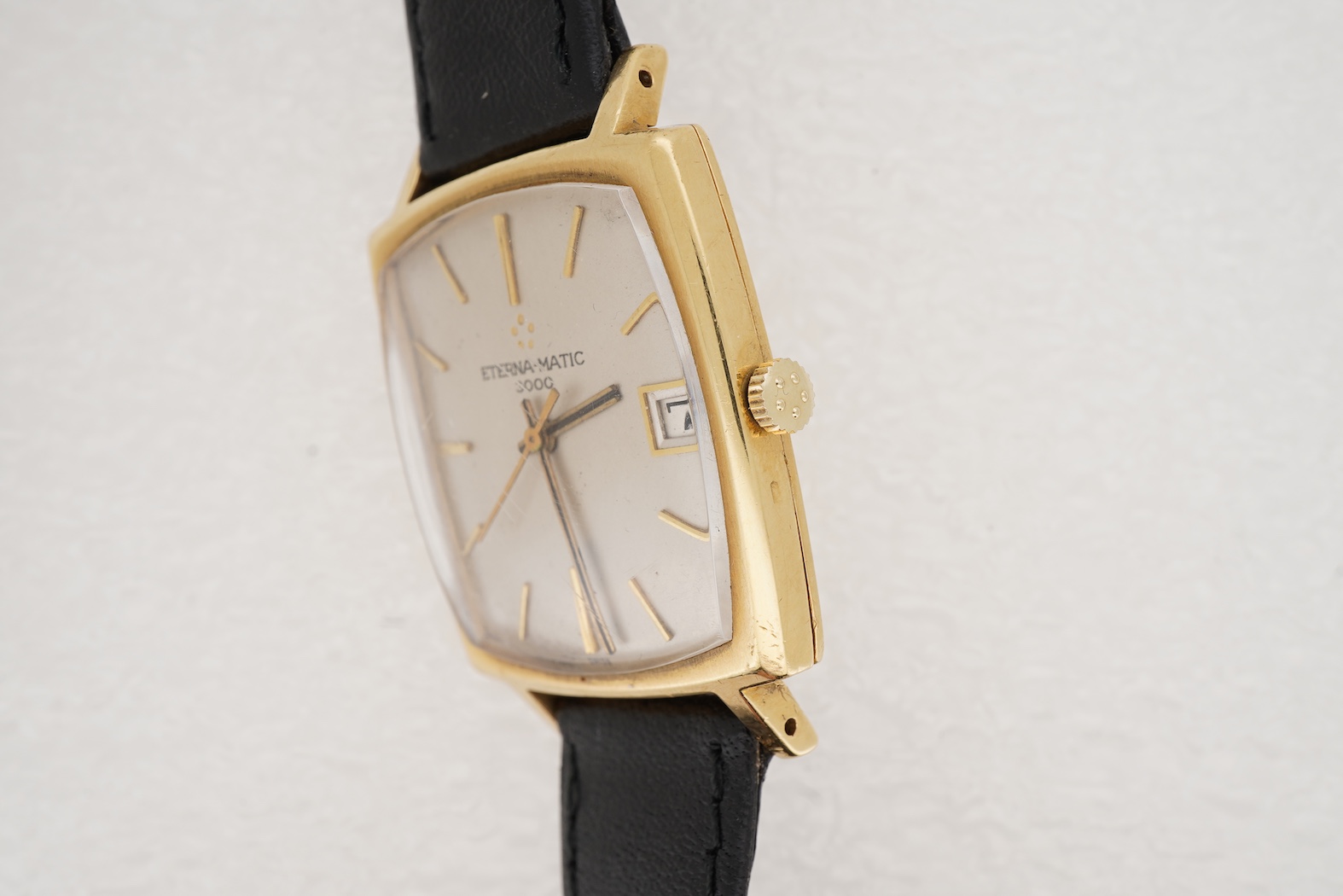 A gentleman's 18ct gold Eterna-Matic 3000 wrist watch, with baton hour marker, centre seconds hand and calendar aperture at 3 o’clock, on an associated black leather strap